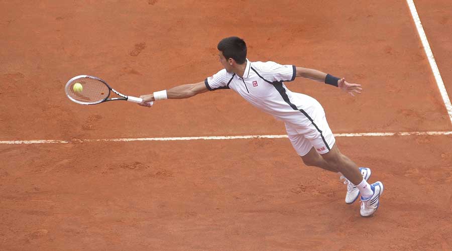 Male tennis player stretching to reach a return.